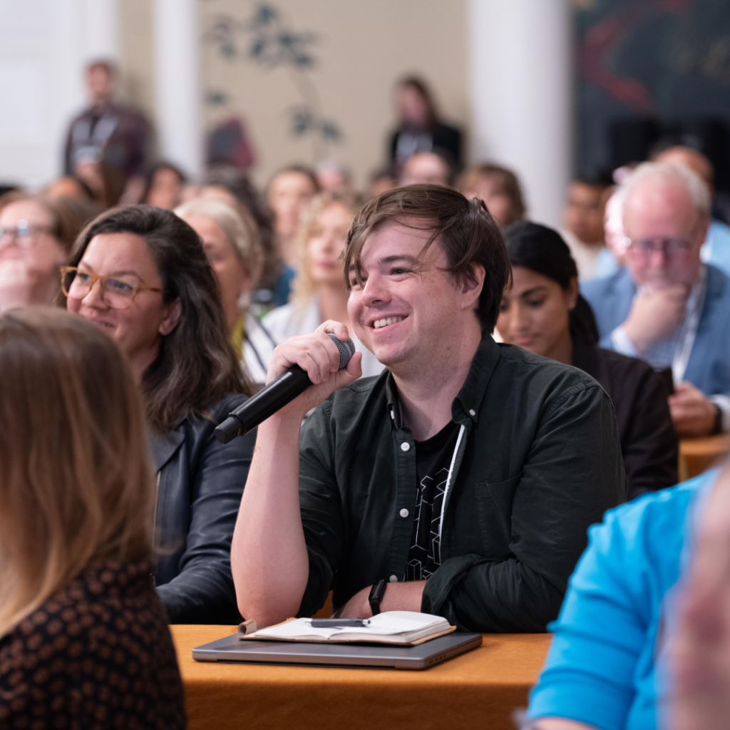 A Summit attendee smiling while holding a microphone